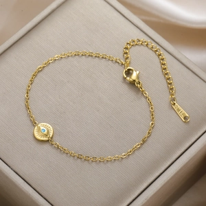 Macro shot of gold stainless steel bracelet with blue evil eye pendant on a display box