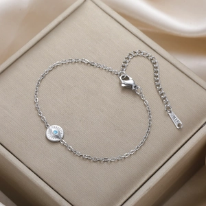 Macro detail of silver stainless steel evil eye bracelet with blue crystal and lobster clasp