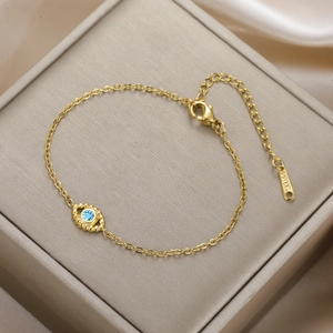 Detail of gold evil eye bracelet with blue stone and lobster clasp on jewelry box