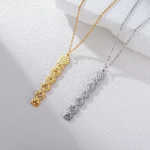 Macro shot of gold and silver 7 chakra symbol bar pendants on a textured stone surface
