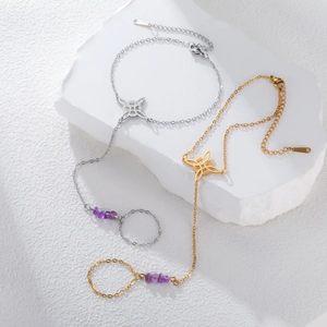 Detail of gold and silver slave bracelets with clover charms and purple crystals