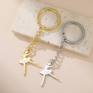 Porte-clés ballerine élégant en or et argent sur une surface en pierre beige chic