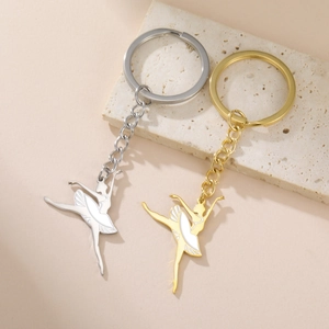 Détail de porte-clés ballerine en or et argent avec émail blanc sur une plaque en pierre