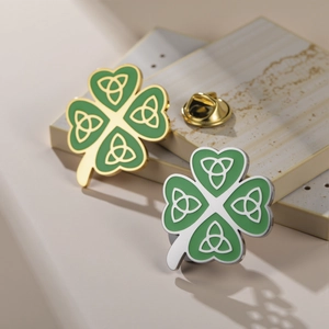 Green enamel four-leaf clover lapel pins with gold and silver trim on a stone plate