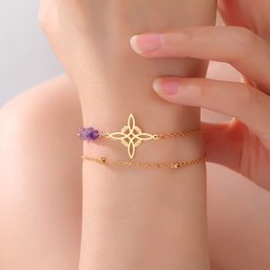 Detail of a double-layer 18K gold-plated bracelet featuring a purple crystal and geometric charm