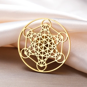 Detailed close-up of golden Metatron Cube hollow brooch on luxury silk fabric background