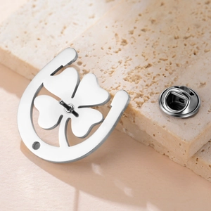 Polished 304 stainless steel four-leaf clover brooch pin on beige stone background
