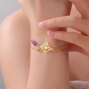 Detail of gold double-layer bracelet with Celtic knot pendant and purple crystal stones