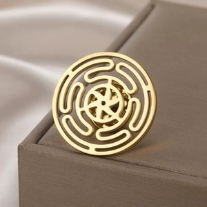 Close-up of golden stainless steel labyrinth brooch with hollowed-out geometric pattern