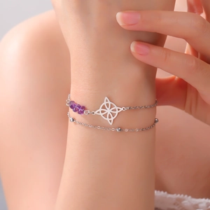 Detail of double-layer stainless steel bracelet with purple crystal and floral pendant