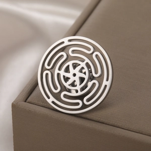 Macro shot of stainless steel cutout brooch with maze pattern and butterfly clutch back