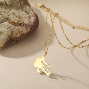 Makroaufnahme eines goldenen Eiskunstlauf-Silhouettenanhängers an einer Edelstahlkette