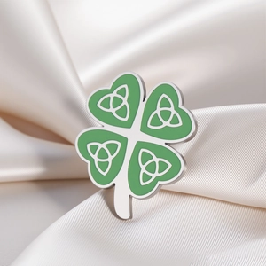 Macro view of a silver shamrock brooch with green enamel and Celtic Triquetra knots