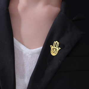 Detailed view of a gold-toned Hamsa Hand brooch pinned to a black suit lapel