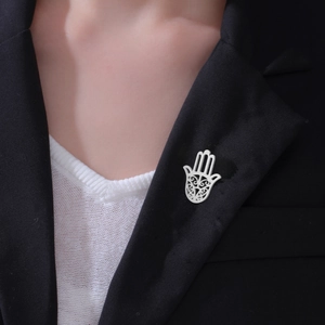 Silver Hamsa Hand brooch with hollow pattern pinned on a black suit lapel detail