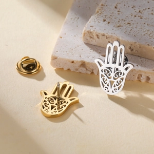 Detailed close-up of gold and silver Hamsa Hand lapel pins with hollow patterns on stone