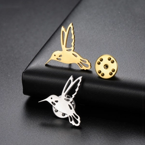 Detail view of gold and silver hummingbird brooches with hollow design and butterfly clasp