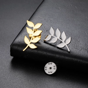 Detailed close-up of leaf-shaped brooches in gold and silver finish with butterfly clutch