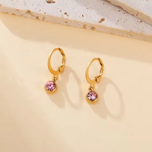 Detailed macro view of golden hoop earrings with clear pink round crystal pendants