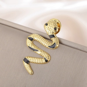 Macro detail of golden snake brooch with black enamel scales and gem eyes on satin
