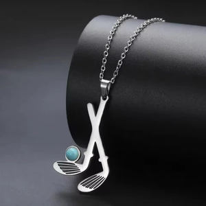 Detail of golf pendant necklace with crossed clubs and turquoise bead on black stand