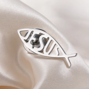 Détail de la broche poisson Ichthys Jésus en acier argenté sur fond de soie beige