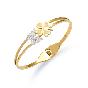 Detail of gold titanium bangle with clover charm and sparkling zircon butterfly pendant