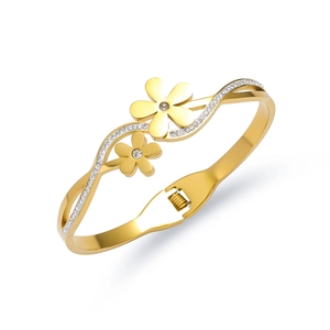 Macro-opname van gouden roestvrijstalen open armband met kristallen bloemmotief