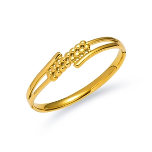 Dettaglio di un bracciale dorato traforato a doppio strato con decorazione a sfere