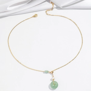 Collana con perla barocca, ciondolo in pietra verde e catena dorata raffinata