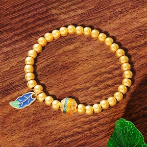 Goldenes Retro-Perlenarmband mit blau-grünem Blattanhänger auf edler Holzoberfläche