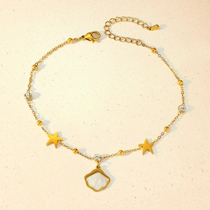 Detail of gold ankle chain with star and shell charms, lobster clasp, and zircon inlays
