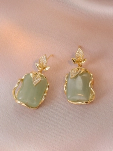 Macro shot of gold leaf earrings with turquoise stones and shimmering zircon inlay