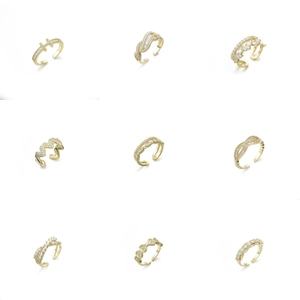Dettaglio di nove anelli regolabili in oro con zirconi in design a cuore e a onde