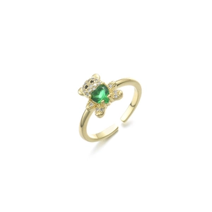 Macro di un anello regolabile dorato con orsetto e una pietra verde a forma di cuore
