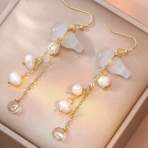Close-up of gold tassel earrings with freshwater pearls and gourd-shaped pendants