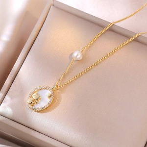 Detail van gouden kattenhanger met parelmoer inleg en parelaccent op ketting