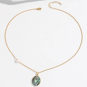 Detailopname van de gouden schelphanger ketting met een zijparel en karabijnslot
