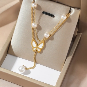 Collana a doppio strato dorata con farfalla e perle bianche su sfondo di seta