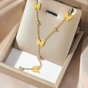 Dettaglio della collana con farfalla dorata e zirconi scintillanti su espositore in raso