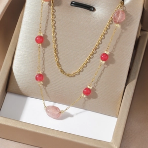 Close-up of double-layer gold chain necklace with red beads and pink oval agate stones