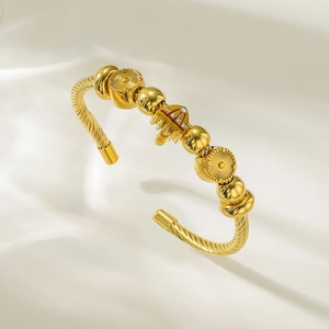 Gros plan du bracelet jonc torsadé doré avec pendentifs diamants sur soie blanche