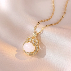 Dettaglio della collana d'oro con pietra ovale bianca e cristalli pavé su seta