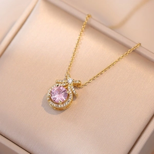 Dettaglio della collana dorata con ciondolo in zircone rosa tondo e fiocco di cristalli