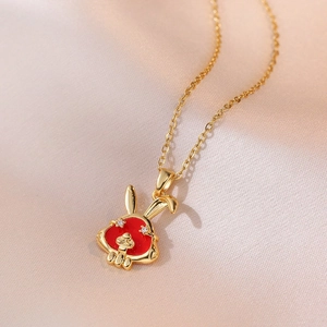 Collar dorado elegante con colgante de conejo rojo y ojos de circón sobre fondo de seda