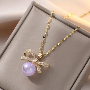 Elegante collana di perle viola con pendente a fiocco in zirconi e acciaio dorato