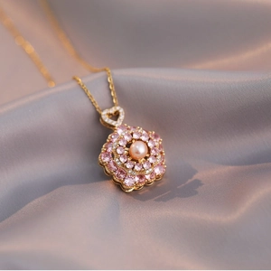 Collier en or élégant avec pendentif fleur en perle rose sur fond de satin violet