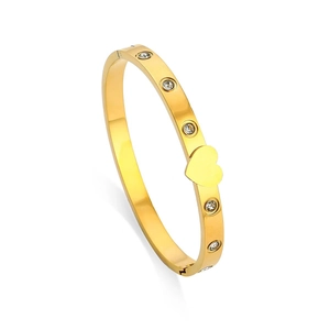 Polished gold butterfly bangle with sparkling zircons and heart charm on white background