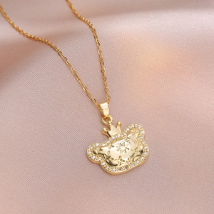 Κοντινό πλάνο χρυσού μενταγιόν αρκουδάκι με κορώνα και κρύσταλλα σε ροζ μετάξι