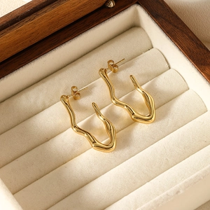 Boucles d'oreilles vagues irrégulières dorées minimalistes dans un écrin de luxe